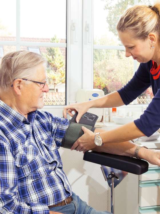 Senior bekommt ein Blutdruckmessgerät von einer Frau angelegt